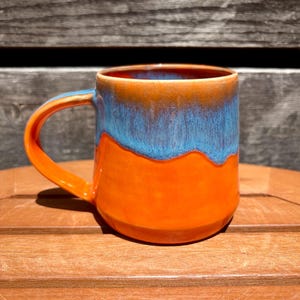 Taza de cerámica naranja y azul en ángulo