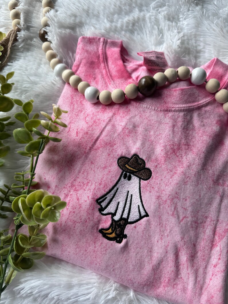 May include: Pink tie-dye t-shirt with an embroidered ghost wearing a cowboy hat.