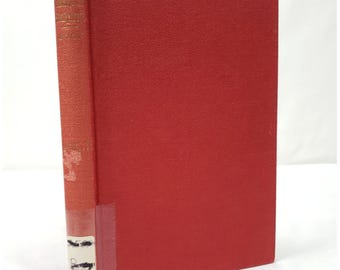 May include: A hardcover book with a red cover and spine. The spine has gold lettering and a small sticker. The book's cover is a solid, textured red. The book is closed and upright.