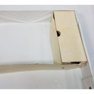 Op de afbeelding: Een open, lege witte doos met een beige kartonnen inzet. De doos heeft een rechthoekige vorm met een gevouwen rand. De kartonnen inzet heeft een rond gat en is licht beschadigd.