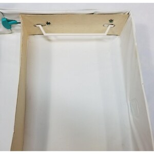 Op de afbeelding: Een open, lege witte doos met een lichtbruin interieur. De doos heeft een witte plastic handgreep en is gemaakt van karton. De doos is rechthoekig en heeft een eenvoudig ontwerp.
