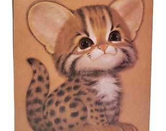May include: A square print featuring a detailed illustration of a small, wide-eyed wild cat kitten with brown fur, dark spots, and a white chest. The kitten has large ears and a light brown background, rendered in a soft, painterly artistic style.