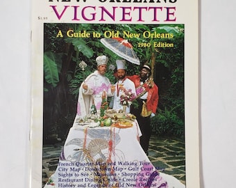 May include: A vintage travel guide titled "The New Orleans Vignette" from 1980. The cover features a colorful image of three people in ornate attire, standing behind a table laden with food. The guide includes maps, sights, dining, and history.