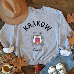 May include: Gray sweatshirt with black text that reads "Krakow Est. 1257 Poland" and a black and white coat of arms graphic.