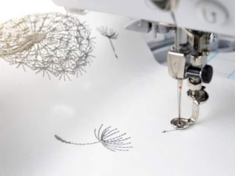 K&ouml;nnte beinhalten: Nahaufnahme einer N&auml;hmaschinennadel, die ein Design von L&ouml;wenzahnblume auf wei&szlig;en Stoff stickt.