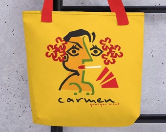 Puede incluir: Bolsa de lona amarilla con asas rojas que presenta una ilustración colorida de la cara de una mujer con flores y el texto "carmen" y "georges bizet".