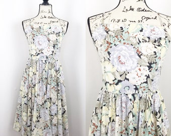 May include: A sleeveless floral print dress with a fitted bodice and a full skirt. The dress is made of a lightweight fabric and has a black background with white, green, and yellow flowers.
