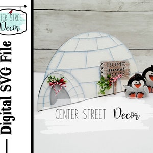 May include: A white wooden igloo with a red and white striped door and a sign that says "Home Sweet Home". Two penguins stand in front of the igloo. The igloo is a digital SVG file.