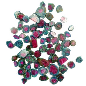 May include: A collection of raw, unpolished gemstone fragments featuring a vibrant contrast between deep magenta-pink centres and surrounding teal-green mineral matrix. These irregular, multi-faceted stones vary in size and shape.