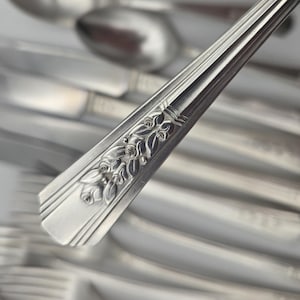 May include: A set of silver flatware with ornate floral designs on the handles. The silverware includes spoons, forks, and knives.