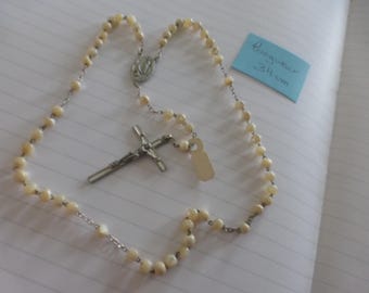 May include: A rosary with cream-colored beads and a silver-toned crucifix. The rosary is approximately 13.4 inches long. The image includes a small tag and a decorative centerpiece.