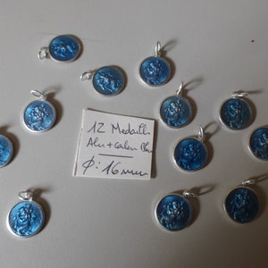 Peut inclure: Douze médaillons argentés avec émail bleu et une image religieuse. Les médaillons mesurent 16 mm de diamètre. Le texte sur la carte indique "12 Médaillons, Alu + Couleur Bleu, Ø: 16mm."