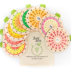 May include: Wooden educational math toys with colorful fruit-themed designs. Each circular piece features numbers and a multiplication table. The set includes a canvas bag with the text "Lace & Learn MATH FRUIT 15".
