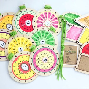 May include: A set of colorful wooden counting circles with numbers 3, 4, 6, 8, 10, 12, and 15. Each circle has a different fruit design and is strung with green yarn. The set also includes wooden shapes with geometric designs and text about the area of a triangle and square.