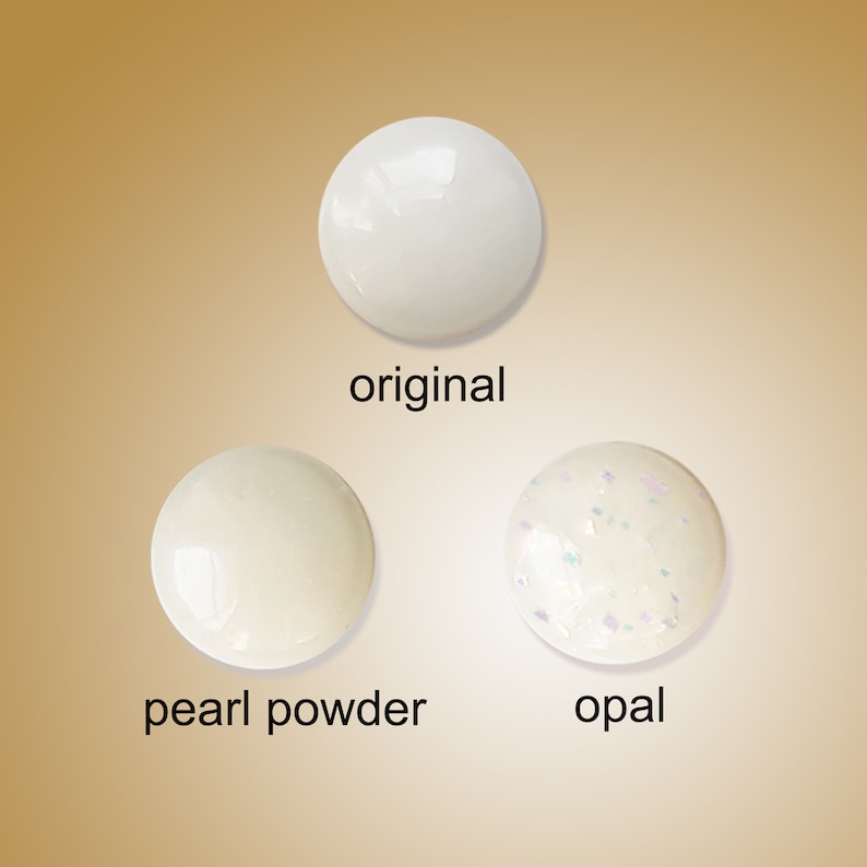 Puede incluir: Tres muestras redondas blancas de esmalte de u&ntilde;as. La primera muestra est&aacute; etiquetada como "original", la segunda como "polvo de perla" y la tercera como "&oacute;palo". La muestra de &oacute;palo tiene un acabado brillante.