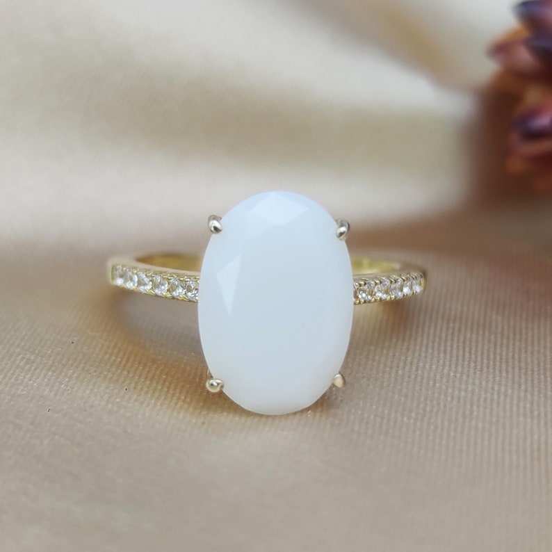 May include: A gold ring with a large oval white stone and a band of small clear stones.