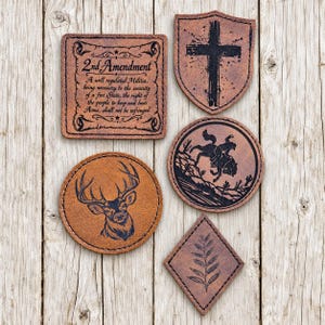 May include: Five brown leather patches with black laser-engraved designs. One square patch features the 2nd Amendment text, a shield patch shows a cross, a round patch depicts a buck, a round patch shows a bucking horse, and a diamond patch has a leaf.