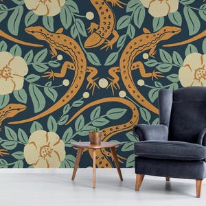 May include: Wallpaper featuring a repeating pattern of orange lizards, cream-colored flowers, and green leaves on a dark blue background. A dark blue armchair and small wooden table are in front of the wallpaper.