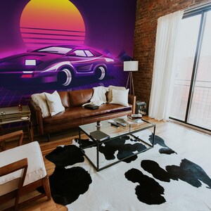 May include: A retro-themed living room with a large wall mural featuring a purple sports car against a sunset backdrop. The room includes a brown leather sofa, a cowhide rug, and a glass coffee table. A large window provides natural light.