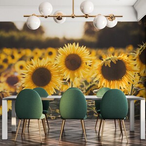 Könnte beinhalten: Ein Esszimmer mit einem Wandbild eines Sonnenblumenfeldes. Der Raum hat einen Holzboden, einen weißen Tisch mit vier grünen Stühlen und einen goldenen Kronleuchter mit weißen Kugeln.