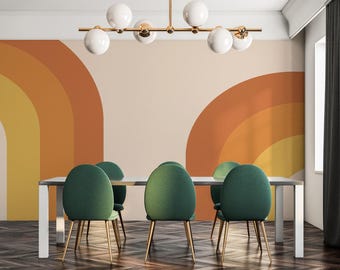 May include: A dining room with a modern, mid-century style. The room features a white wall with a colorful, abstract wallpaper design. The wallpaper features a pattern of orange, yellow, and brown arches. The room has a wooden floor and a glass-top dining table with four green velvet chairs.