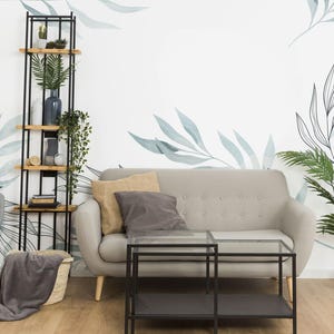 Könnte beinhalten: Ein Wohnzimmer mit einem grauen Sofa, einem grauen Sessel, einem schwarzen Metallregal mit Holzböden, einem schwarzen Glas-Couchtisch und einer Topfpflanze. Die Wand ist mit einer weißen und blauen Blumen-Tapete dekoriert.