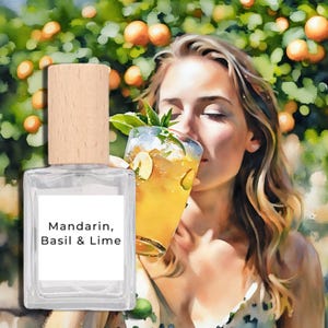 Puede incluir: Un frasco de perfume transparente con tapa de madera y una etiqueta blanca que dice "Mandarin, Basil & Lime". La imagen también presenta a una mujer oliendo un cóctel con rodajas de lima y un fondo de naranjos.