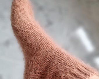 May include: A pair of soft, fuzzy pink socks made from a knitted fabric.