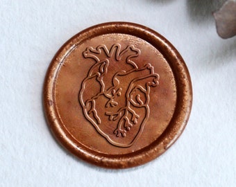 May include: A copper-colored wax seal with a raised design of a heart. The seal is on a white piece of paper.