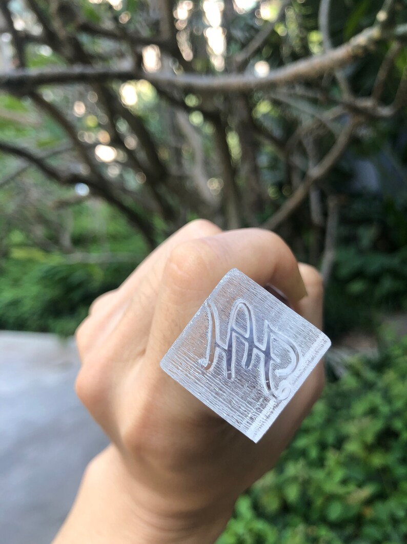 May include: A clear square stamp with the word "HAP" engraved in a cursive font.