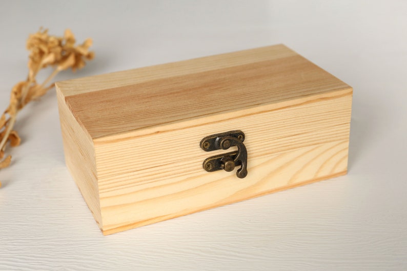 May include: A natural wood box with a hinged lid and a brass latch. The box is made of light wood with a natural finish.