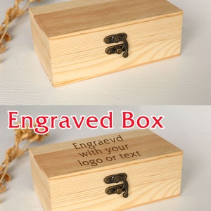 May include: A rectangular wooden box with a hinged lid and a metal clasp. The box is made of light-colored wood and has the text "Blank Box" in red at the top. The second box has the text "Engraved Box" and the text "Engraevd with your logo or text".