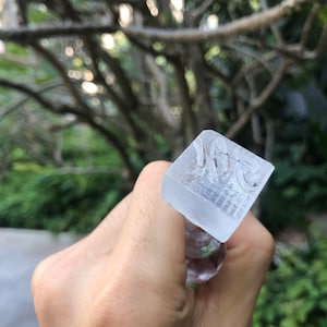 May include: A clear glass stamp with the word "Vote" engraved on the top. The stamp is being held by a hand.