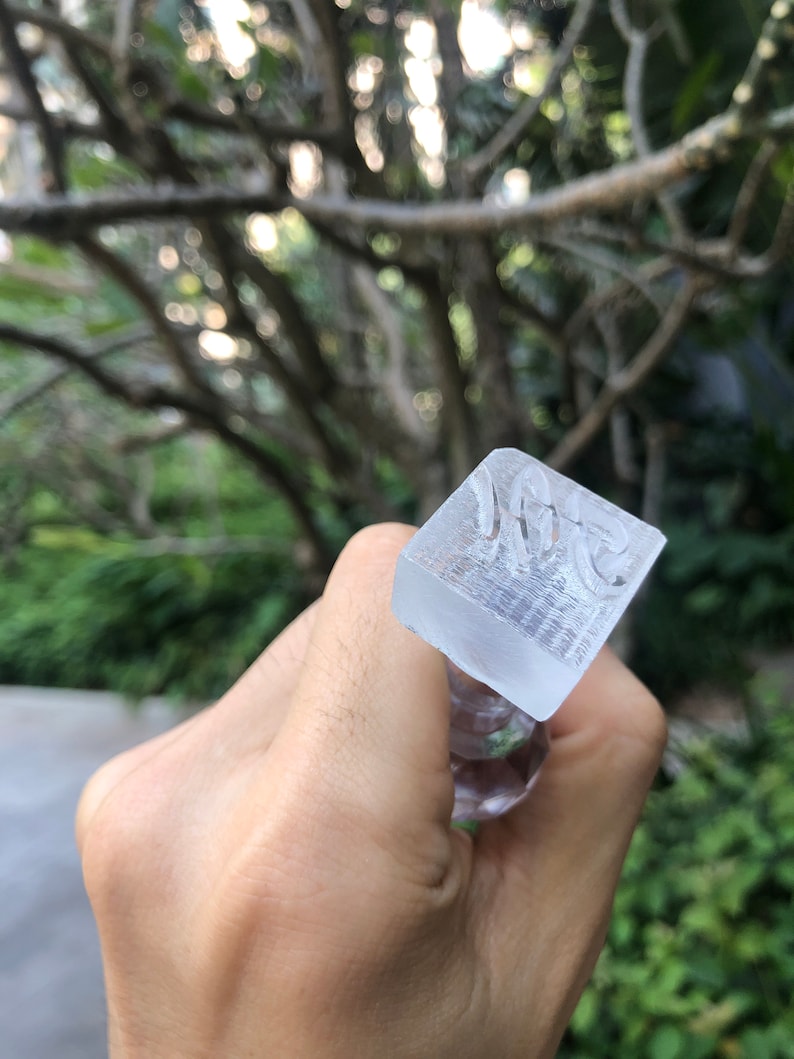 May include: A clear glass stamp with the word "Vote" engraved on the top. The stamp is being held by a hand.