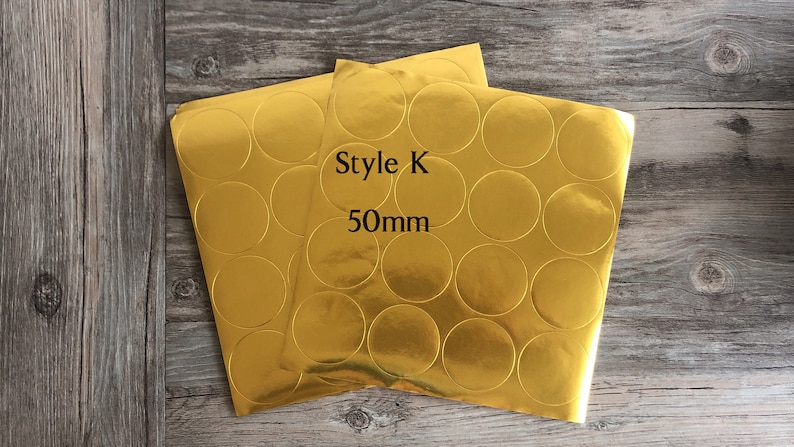 以下が含まれることがあります： 丸い円の金箔ステッカーが2枚。ステッカーの直径は50mmで、「Style K 50mm」とラベル付けされています。