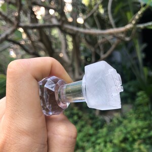 May include: A clear glass bottle stopper with a faceted top and a clear plastic insert. The stopper is designed to fit a bottle of wine or other beverage.