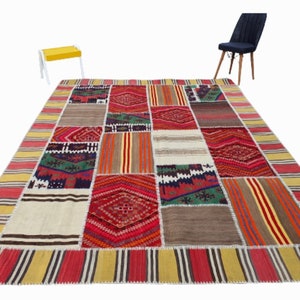 Könnte beinhalten: Ein bunter Patchwork-Teppich mit verschiedenen geometrischen Mustern in Rot, Grün, Blau, Gelb und Weiß. Der Teppich hat einen Fransenrand und ist aus Wolle gefertigt.