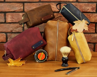 Puede incluir: Seis neceseres de cuero en diferentes colores, incluyendo marrón, rojo, azul y amarillo. Las bolsas tienen cremalleras y están personalizadas con nombres como "Alex" y "182M".