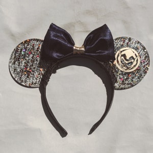Peut inclure: Des oreilles de souris noires et dorées à paillettes avec un nœud en satin noir. Les oreilles sont décorées de paillettes dorées et d'un motif métallique doré.