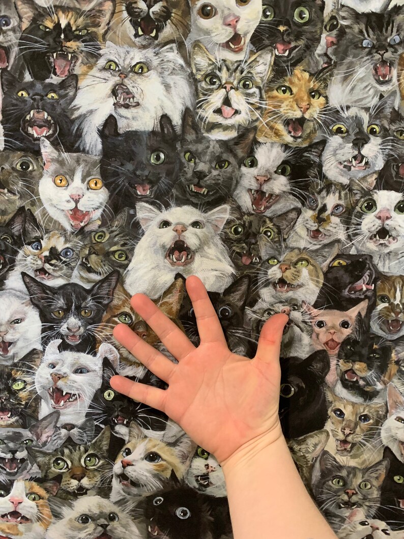 May include: A fabric pattern featuring a multitude of cat faces with open mouths and various expressions. The cats are in shades of gray, black, white, and brown. The image includes a hand for scale.