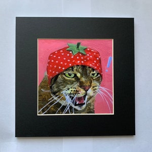 May include: A painting of a cat wearing a red and white strawberry hat. The cat has a pink background and is looking directly at the viewer with an angry expression.