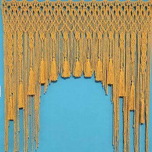 May include: A yellow macrame wall hanging with tassels. The hanging is made of a thick, knotted cord and has a geometric pattern.
