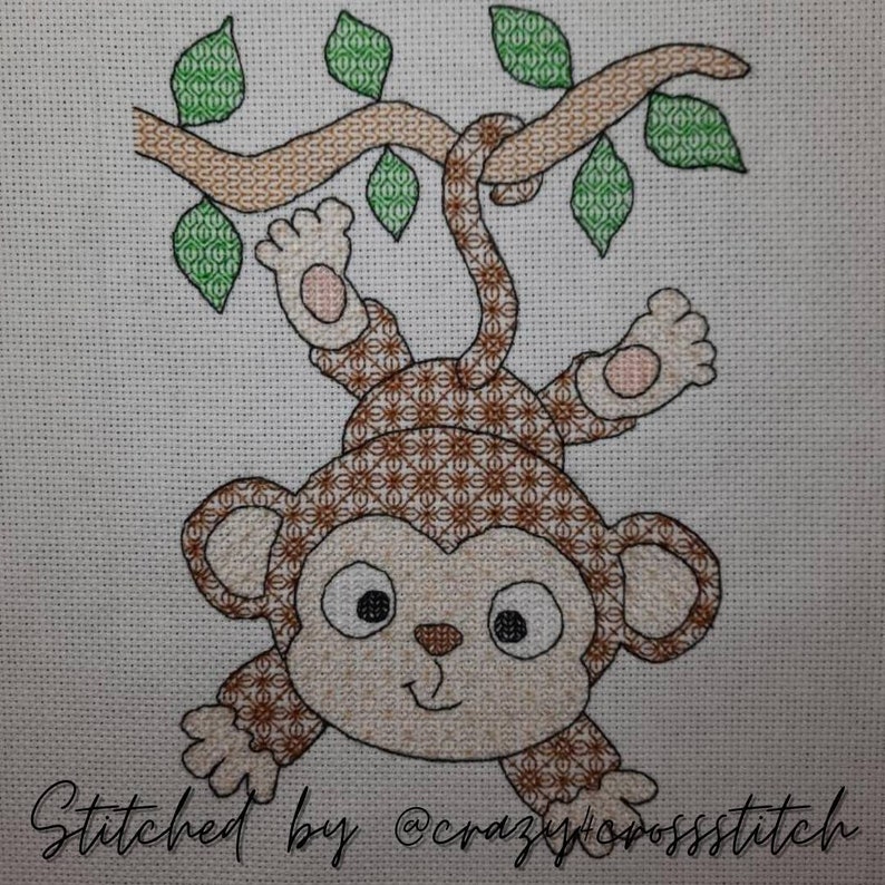 finished stitch by a customer of a blackwork pattern of a cheeky brown monkey with big ears hanging upside down by the tail from a tree branch with green leaves with intricate fill patterns