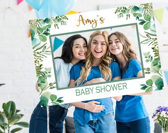 May include: A white photo booth prop with a green leafy border and the text "Amy's Baby Shower". Three women are smiling in the photo cutout.