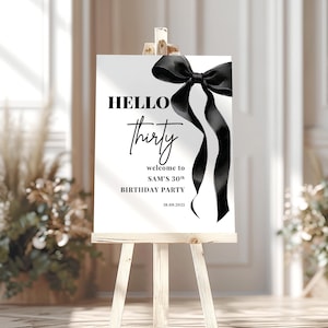 May include: Black and white welcome sign with a black bow and the text "HELLO thirty welcome to SAM'S 30th BIRTHDAY PARTY 18.09.2023"