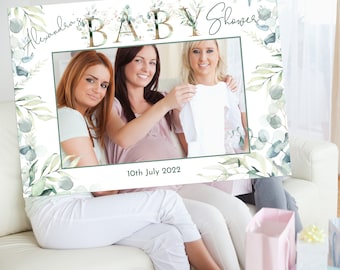 May include: A white photo booth prop with a green leafy border and the text "Alexandra's Baby Shower" and "10th July 2022".