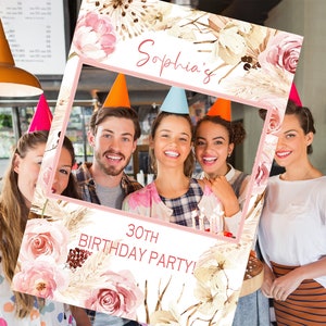 May include: A pink and white photo booth prop with floral and pampas grass designs. The text "Sophia's 30th Birthday Party!" is printed on the prop.
