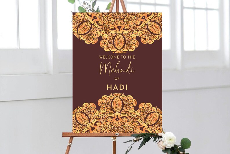 May include: A brown welcome sign with gold ornate designs and the text "Welcome to the Mehndi of Hadi".