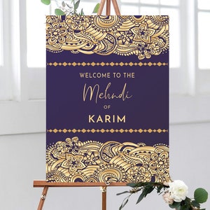 May include: Purple and gold welcome sign with intricate floral designs. The sign reads "Welcome to the Mehndi of Karim".