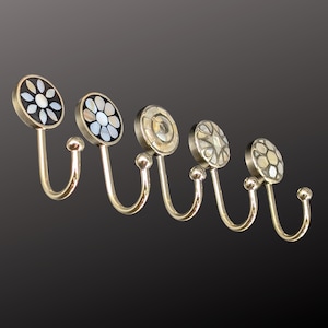 Könnte beinhalten: Set mit fünf dekorativen Wandhaken mit silbernem Finish. Jeder Haken hat ein rundes Design mit verschiedenen Mustern aus Perlmutt. Geeignet zum Aufhängen von Gegenständen im Badezimmer oder Schlafzimmer.